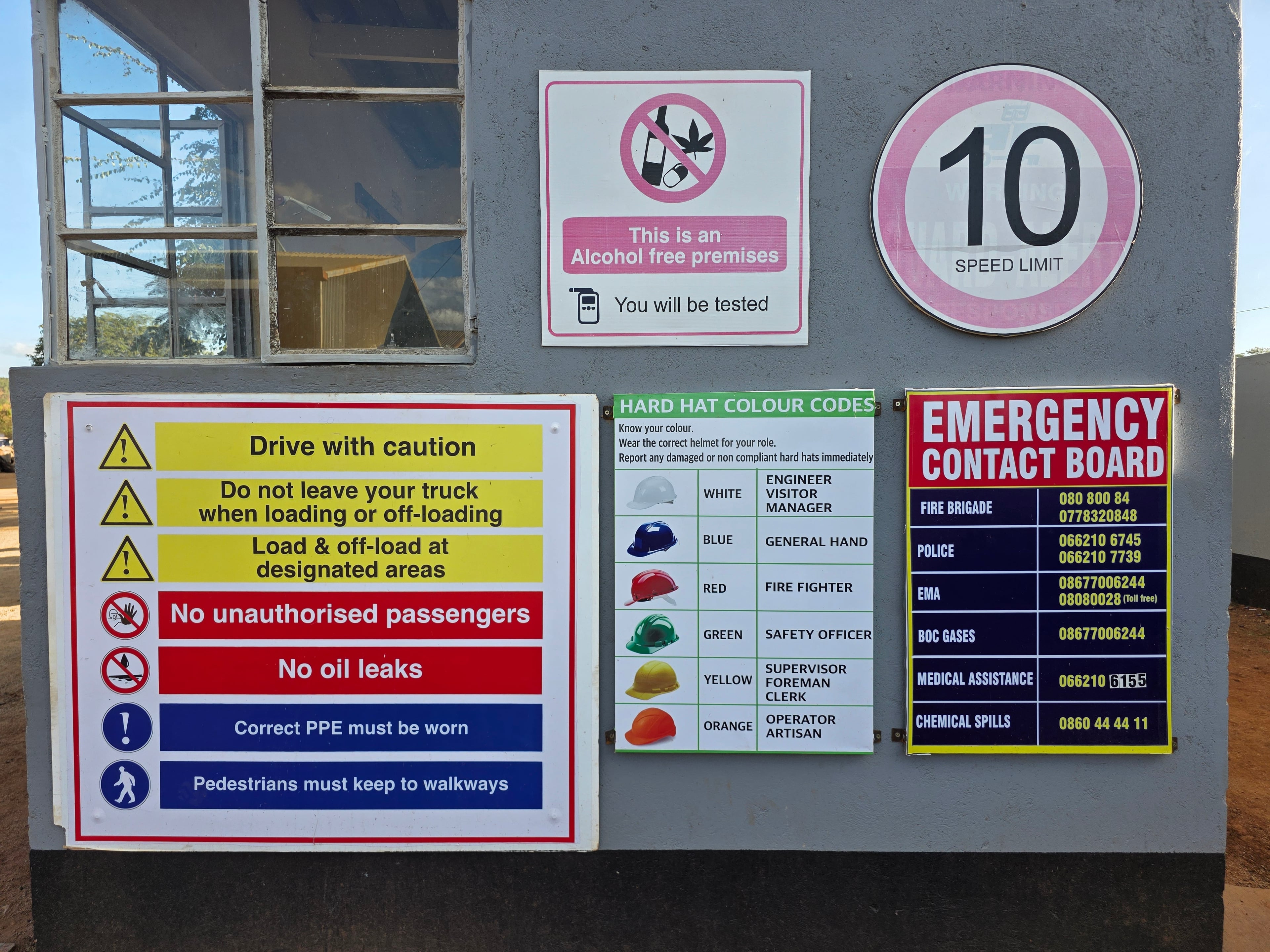 Site safety signage including speed limits, PPE, and emergency contacts.
