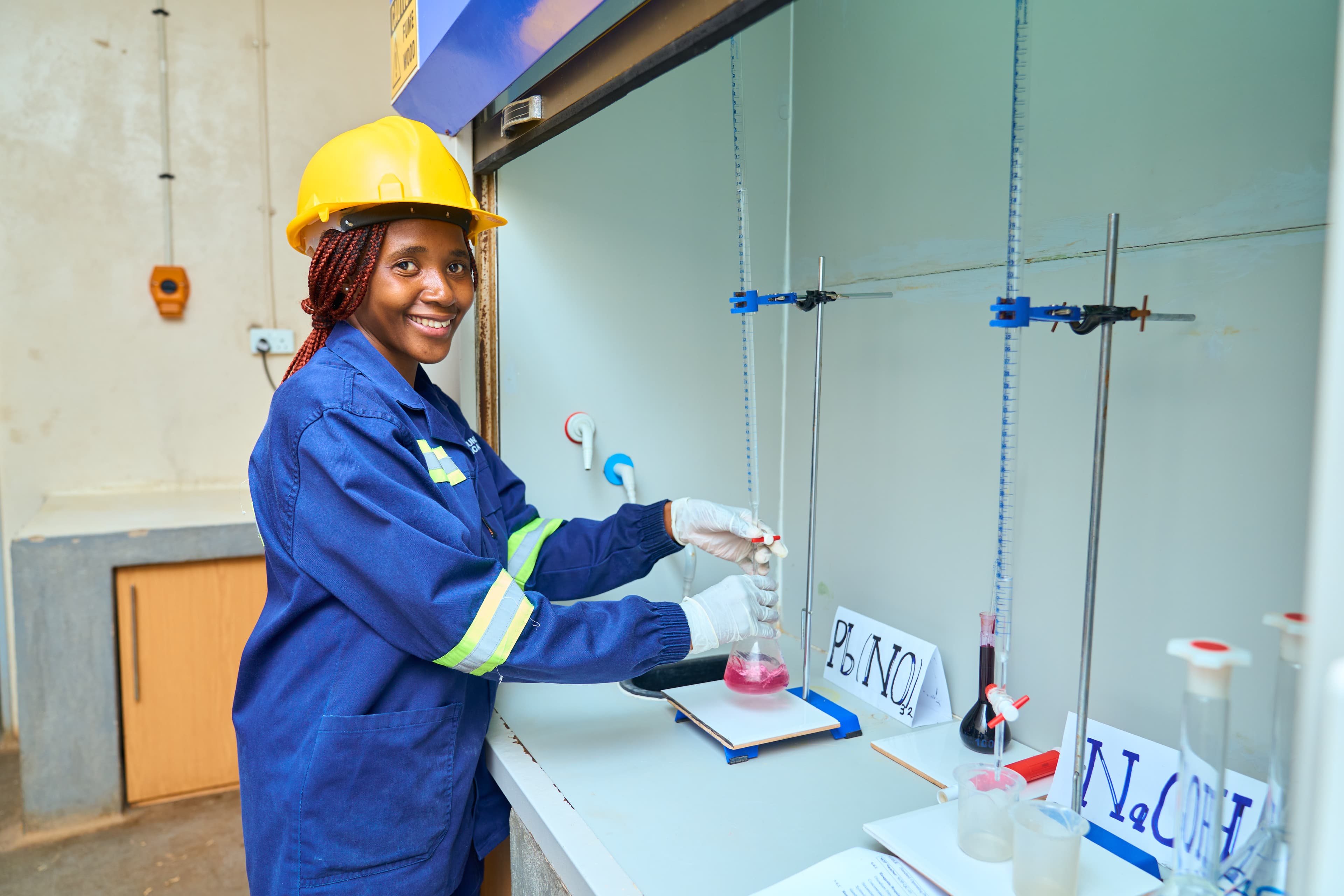 Laboratory technician titrating samples using beakers and calibrated glassware.